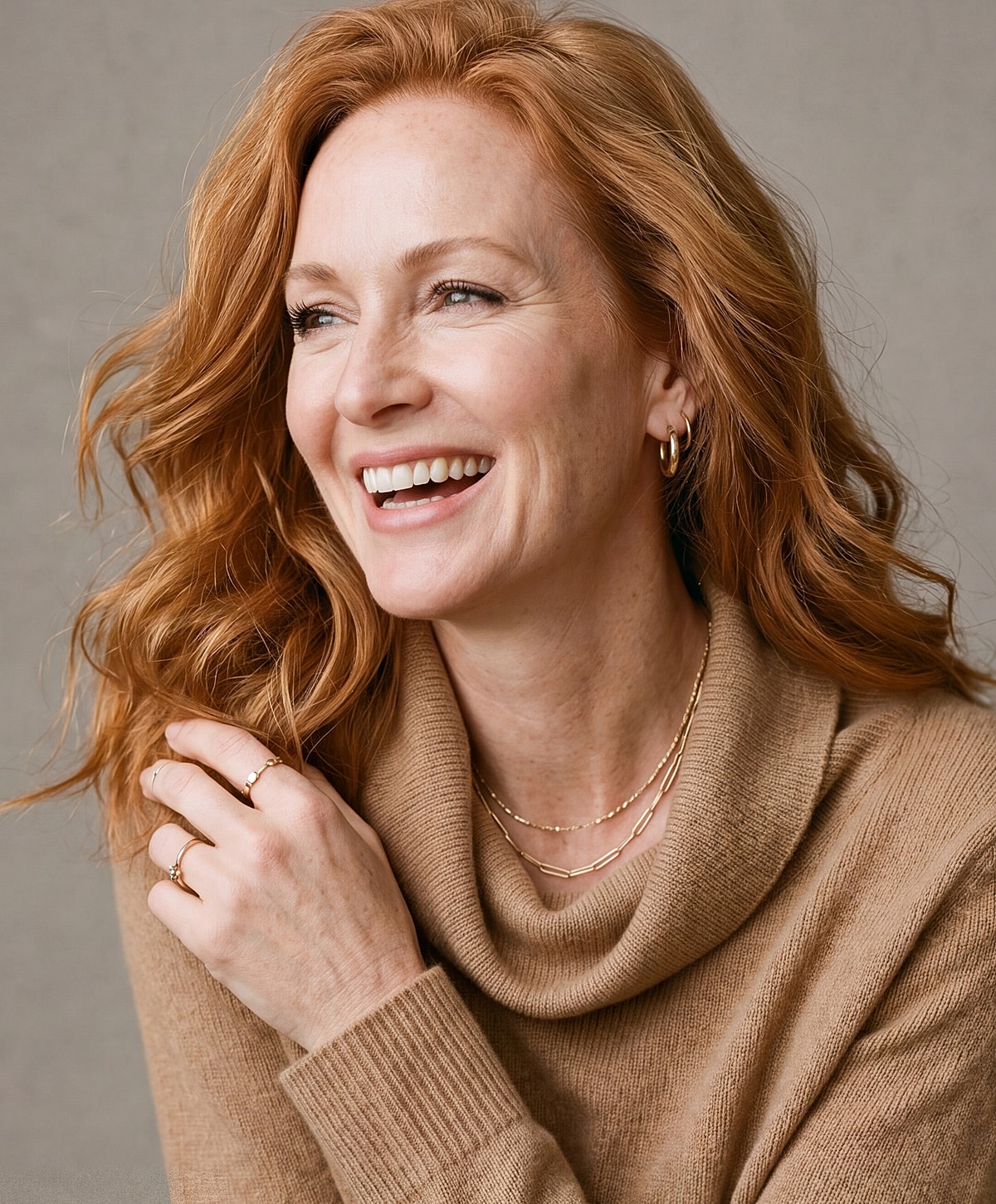 Smiling woman in cozy sweater and jewelry.