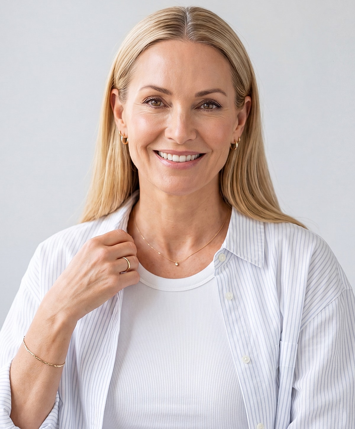 Smiling woman in casual attire with jewelry.