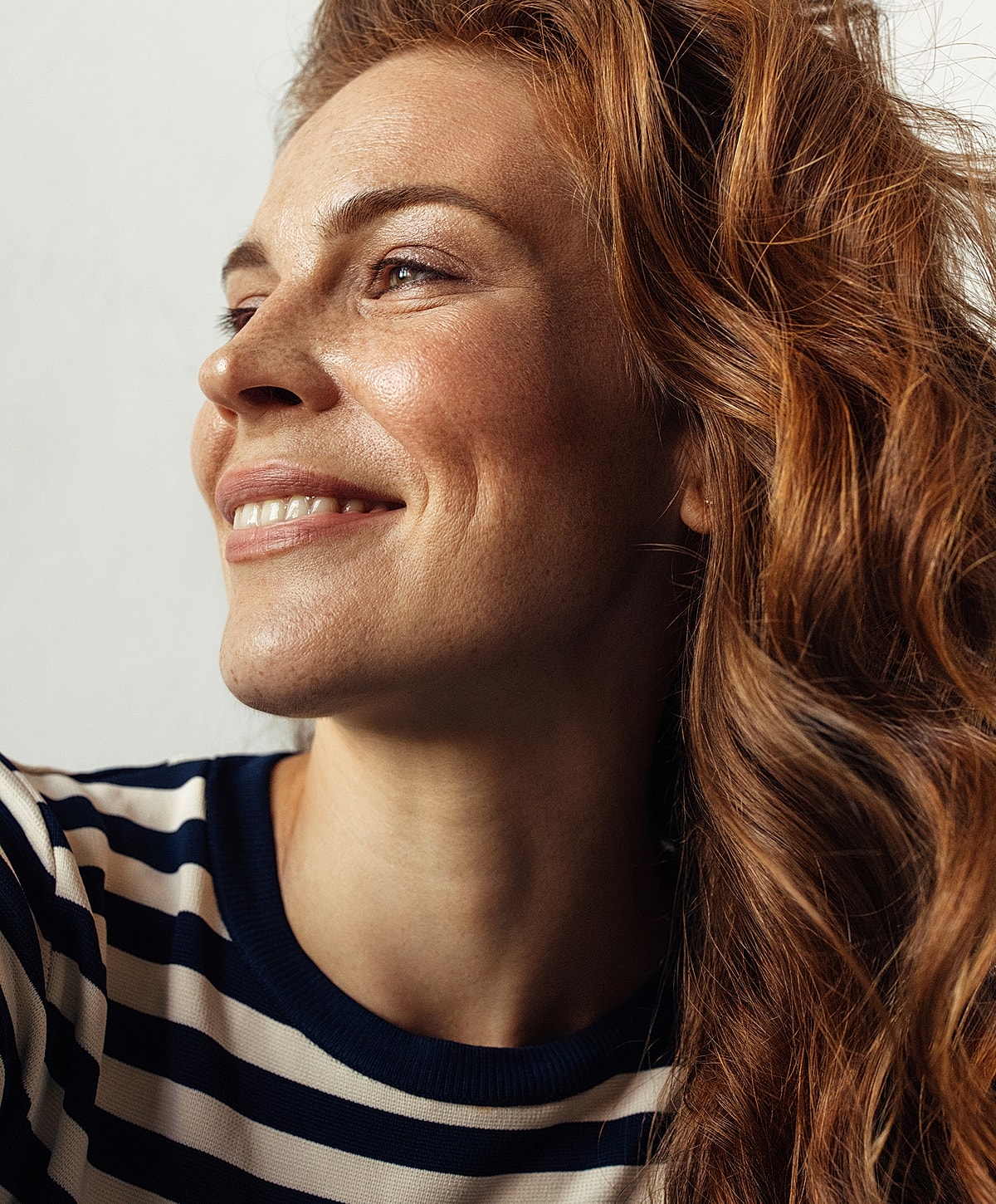 Smiling woman with wavy, red hair.