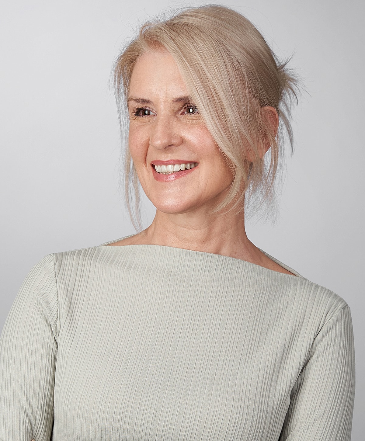 Smiling woman with elegant hairstyle and outfit.