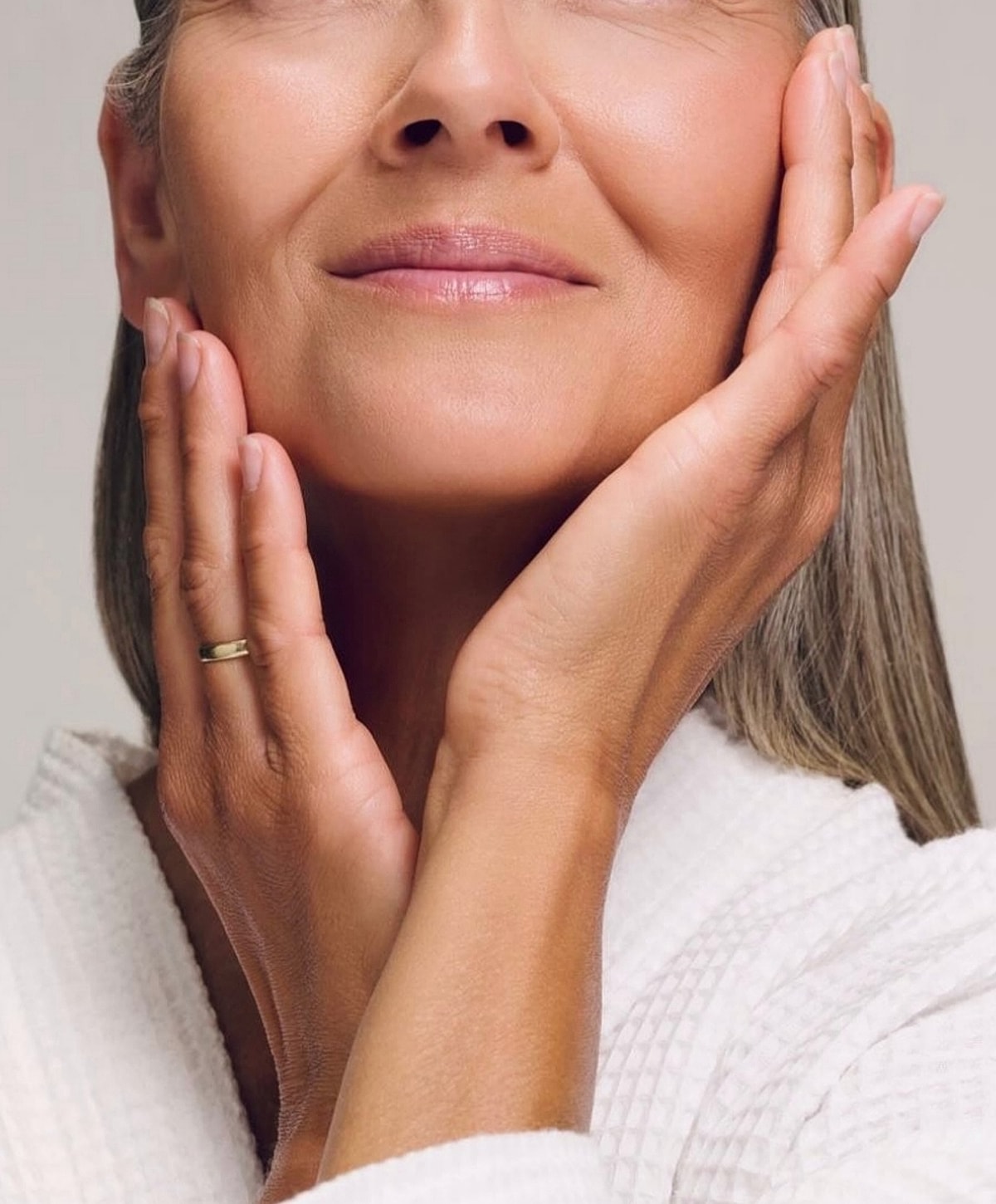 Woman gently touching her face, showcasing skincare.