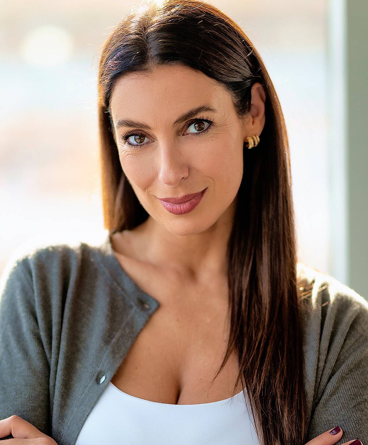 Woman with long hair, smiling in natural light.
