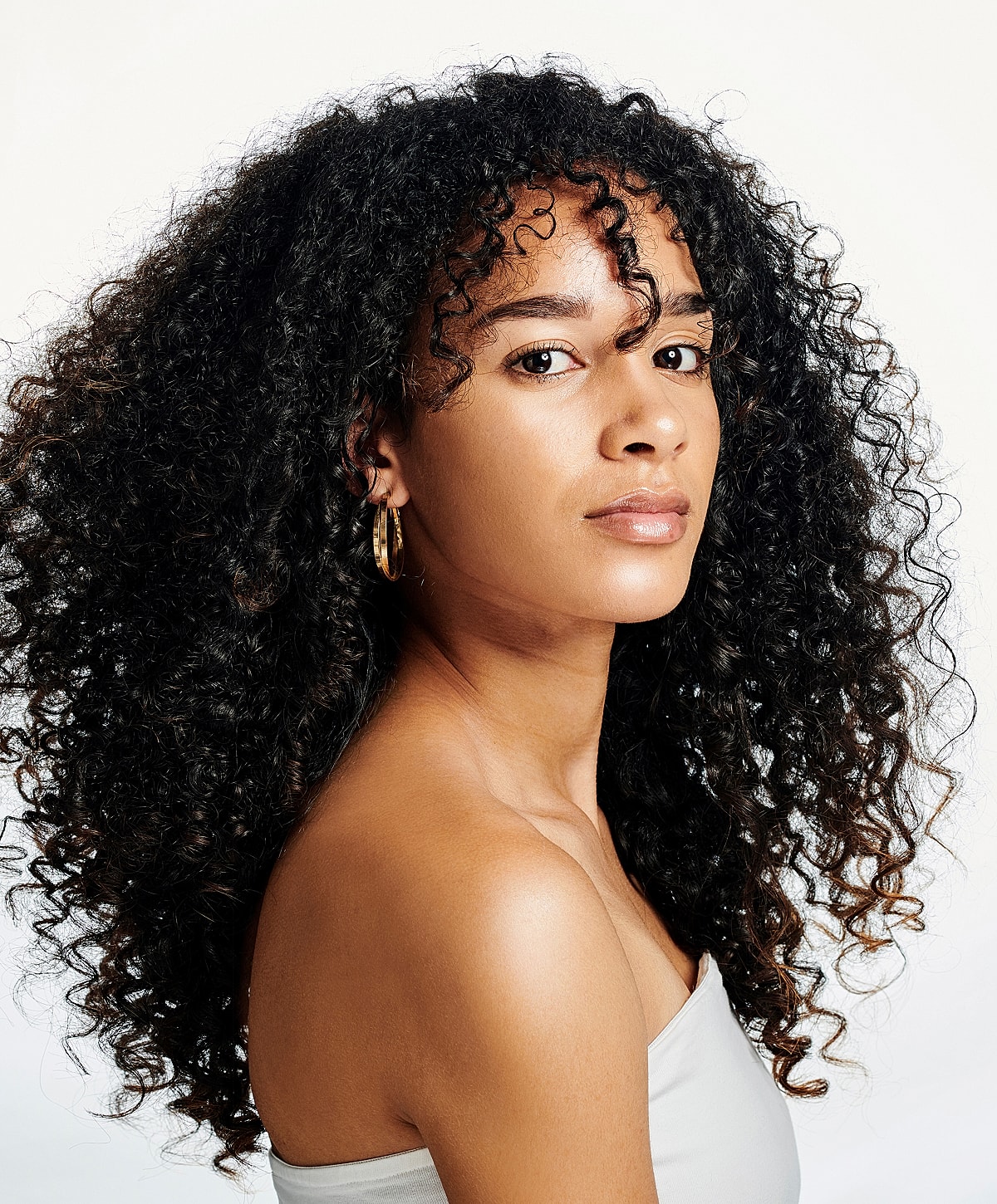 Person with beautiful curly hair and earrings.