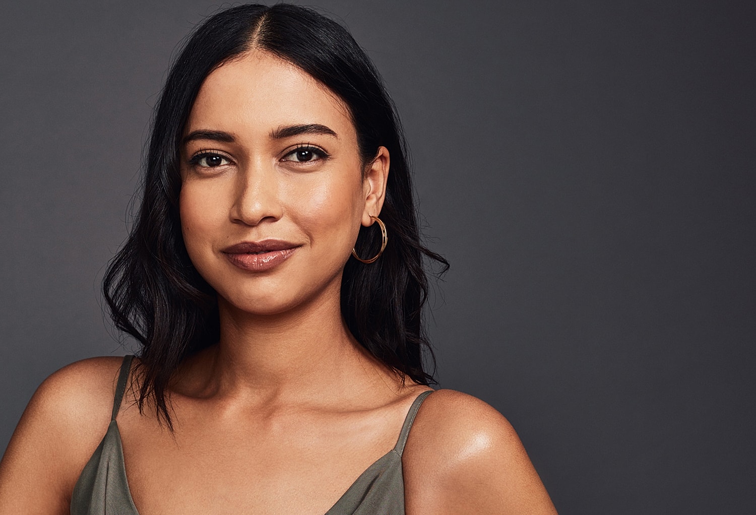 Smiling woman with dark hair and hoop earrings.