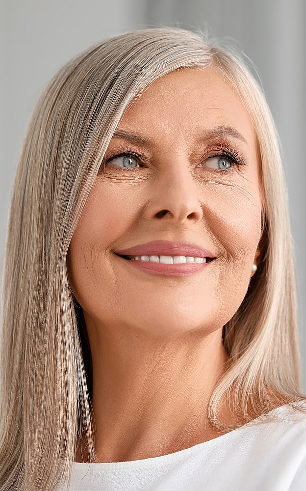 Smiling mature woman with long silver hair.