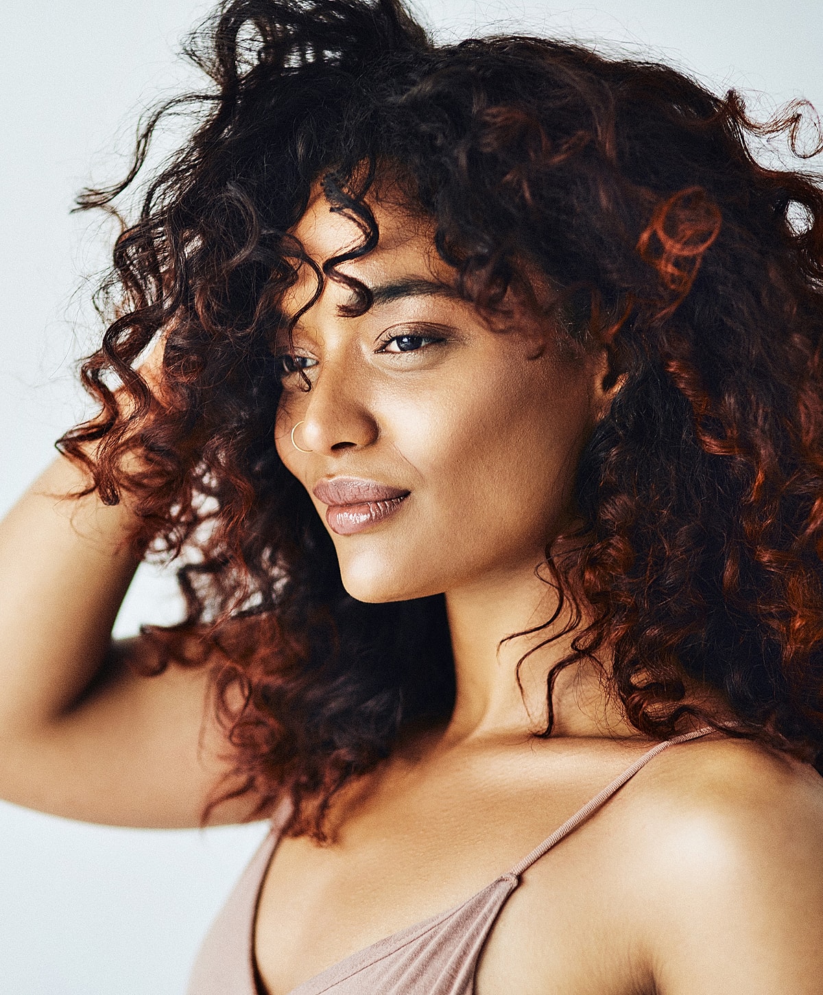Woman with curly hair in soft lighting.