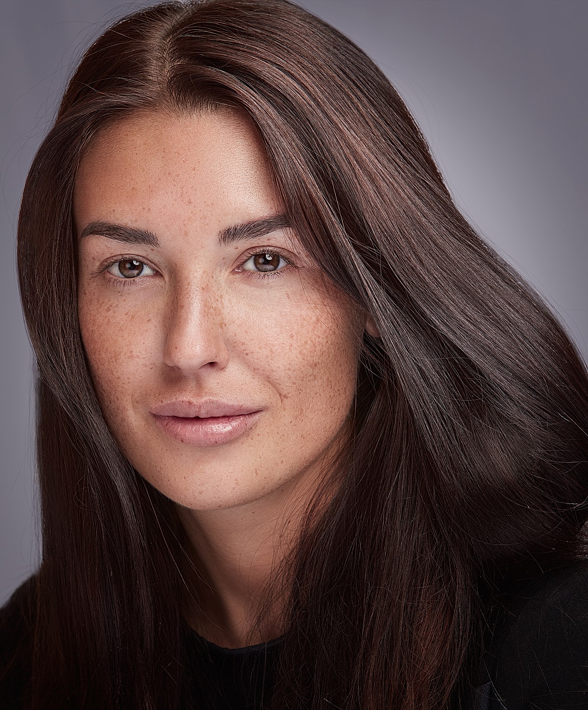Female model with long, dark hair and freckles.