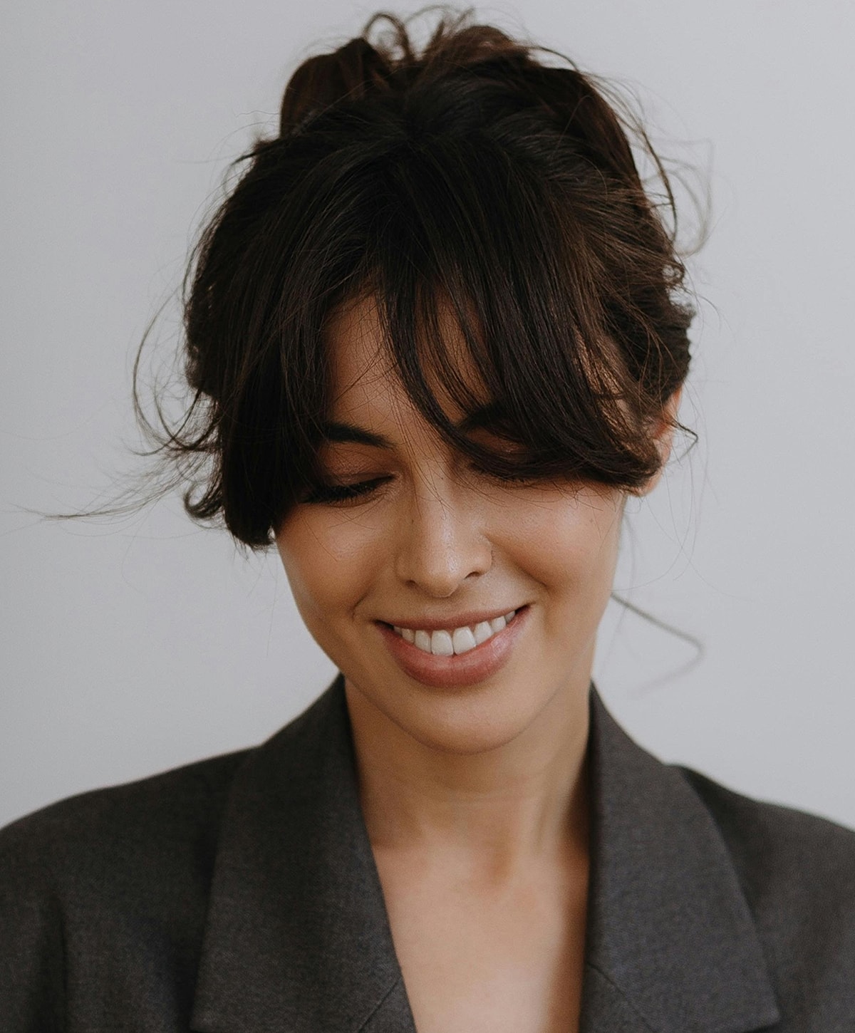 Woman smiling with messy bun hairstyle.