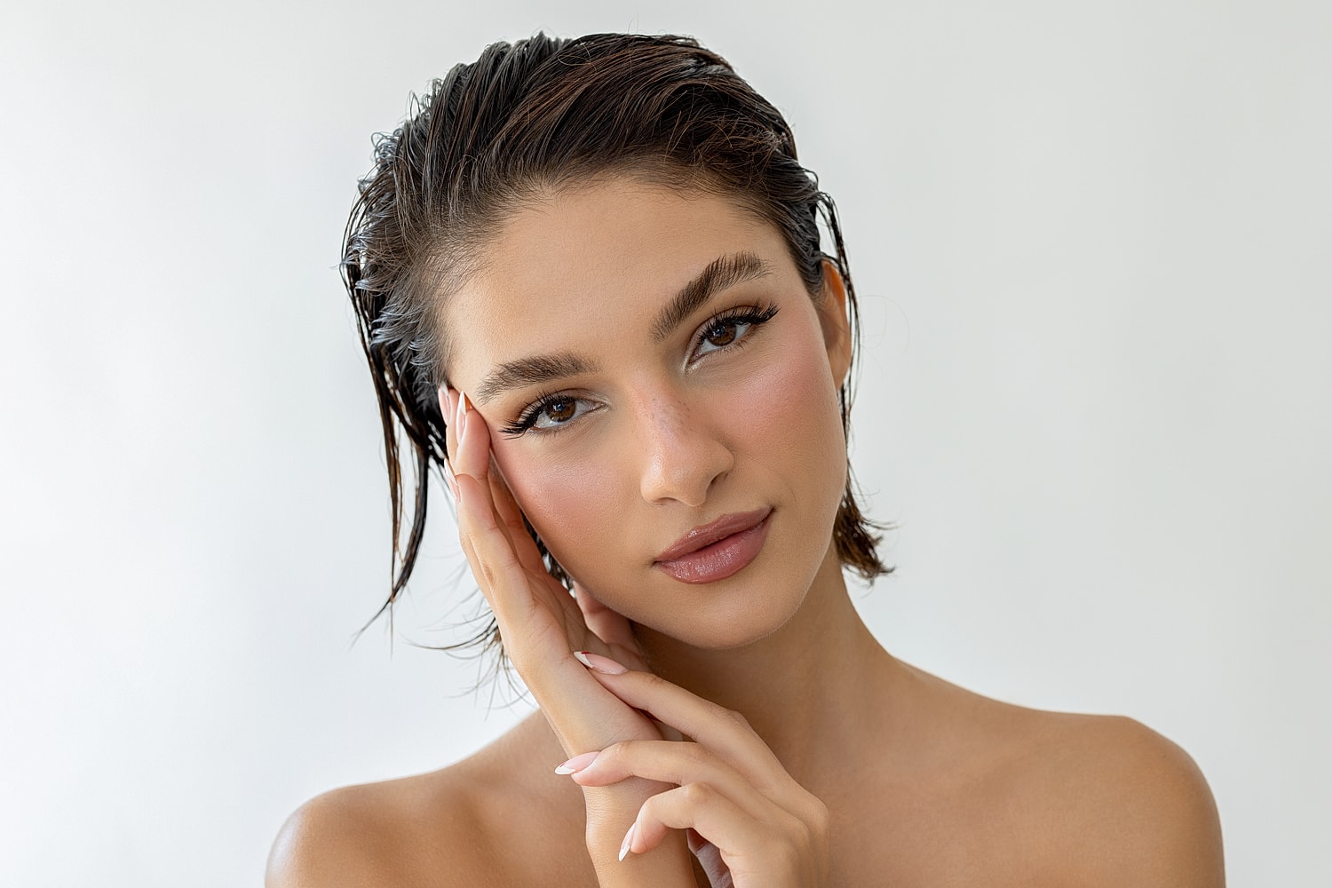 Young woman with fresh makeup against neutral background.