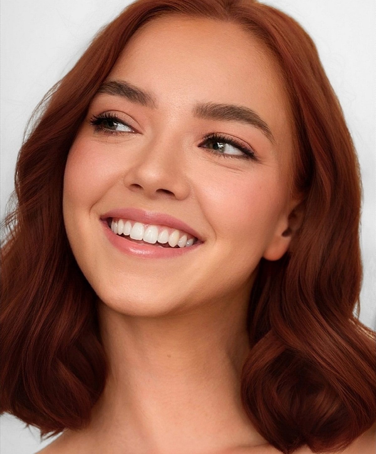 Smiling woman with wavy reddish-brown hair.