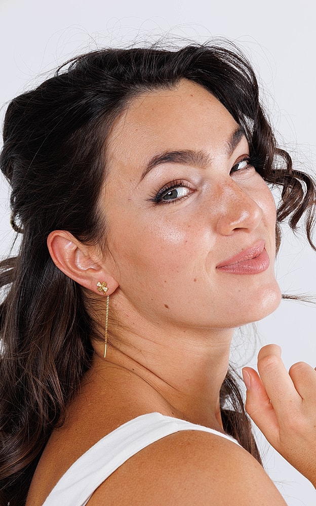 Woman smiling with earrings and curly hair.