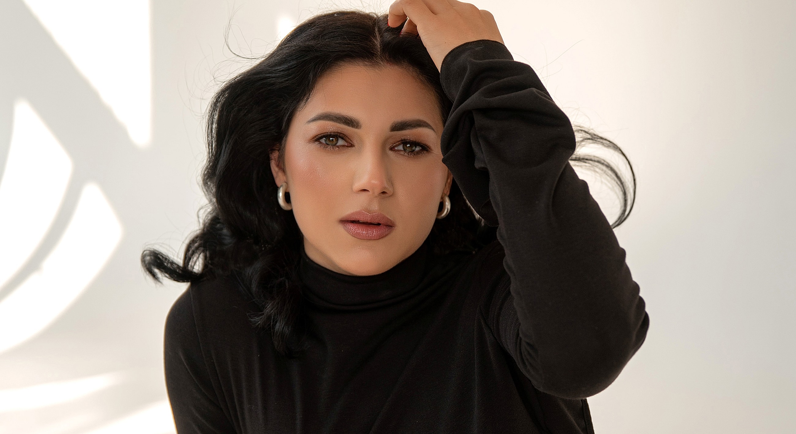 Woman in black attire with wavy hair.
