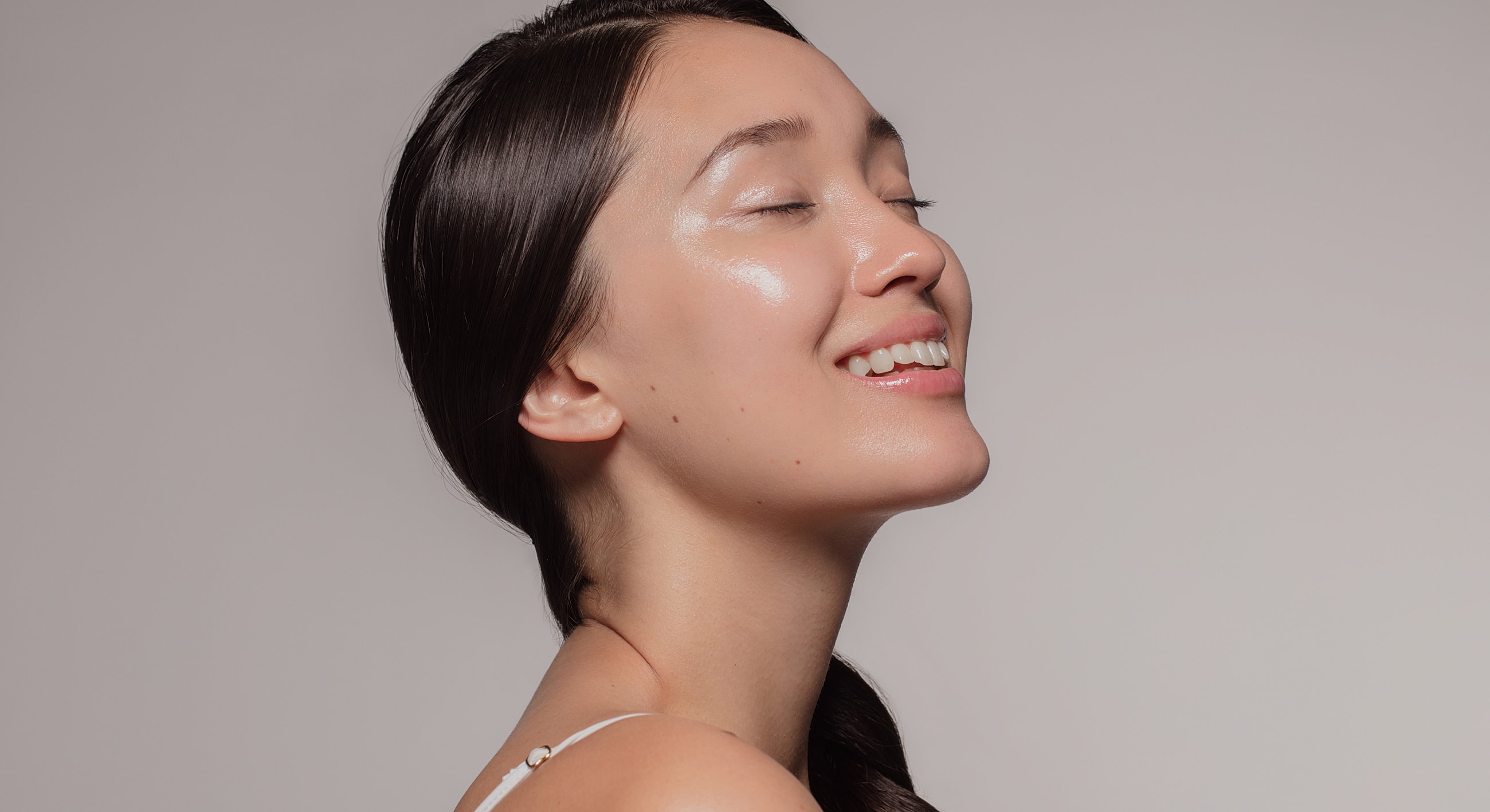 Smiling woman with glowing skin, profile view.