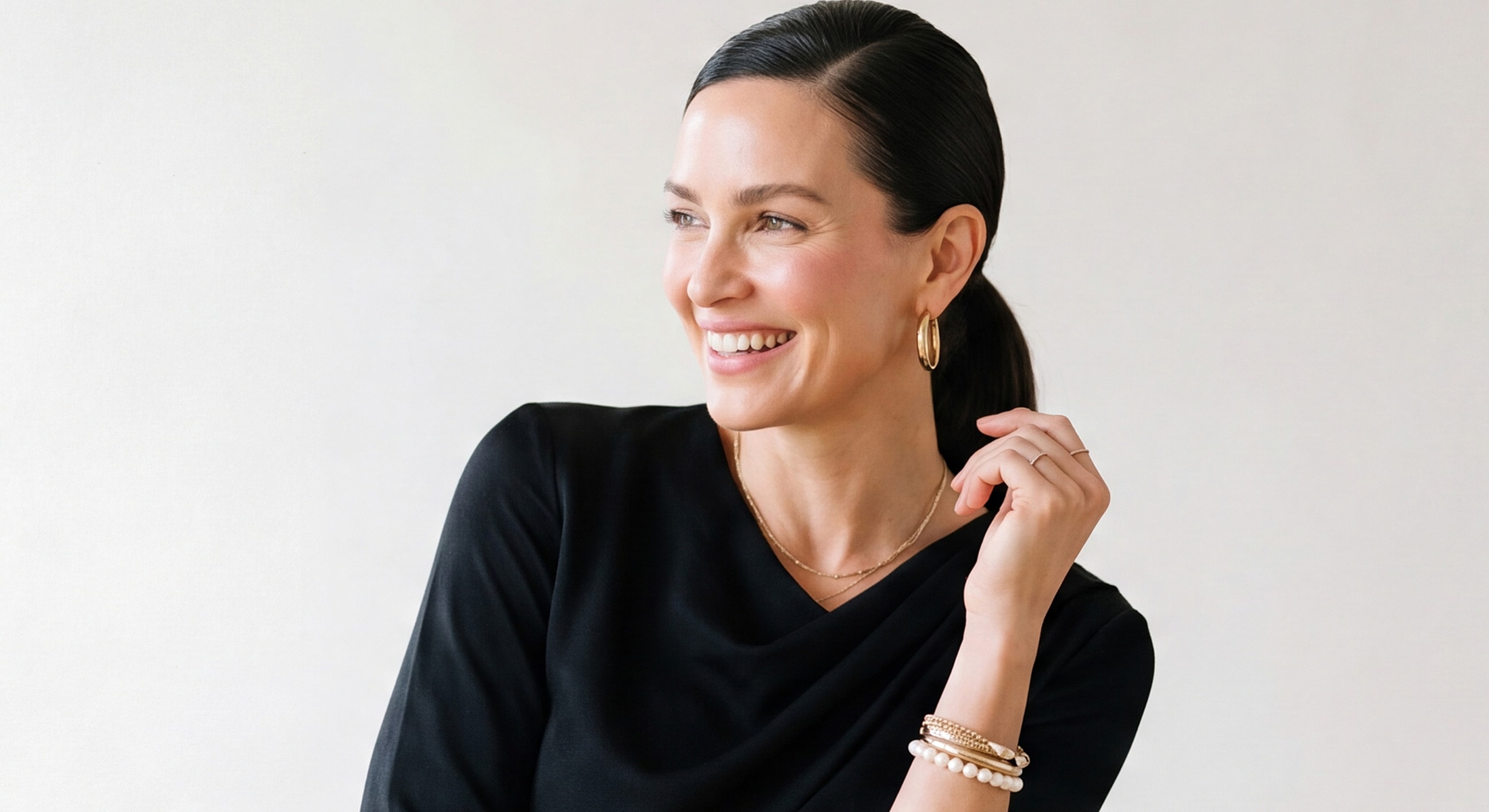 Smiling woman wearing jewelry against neutral background