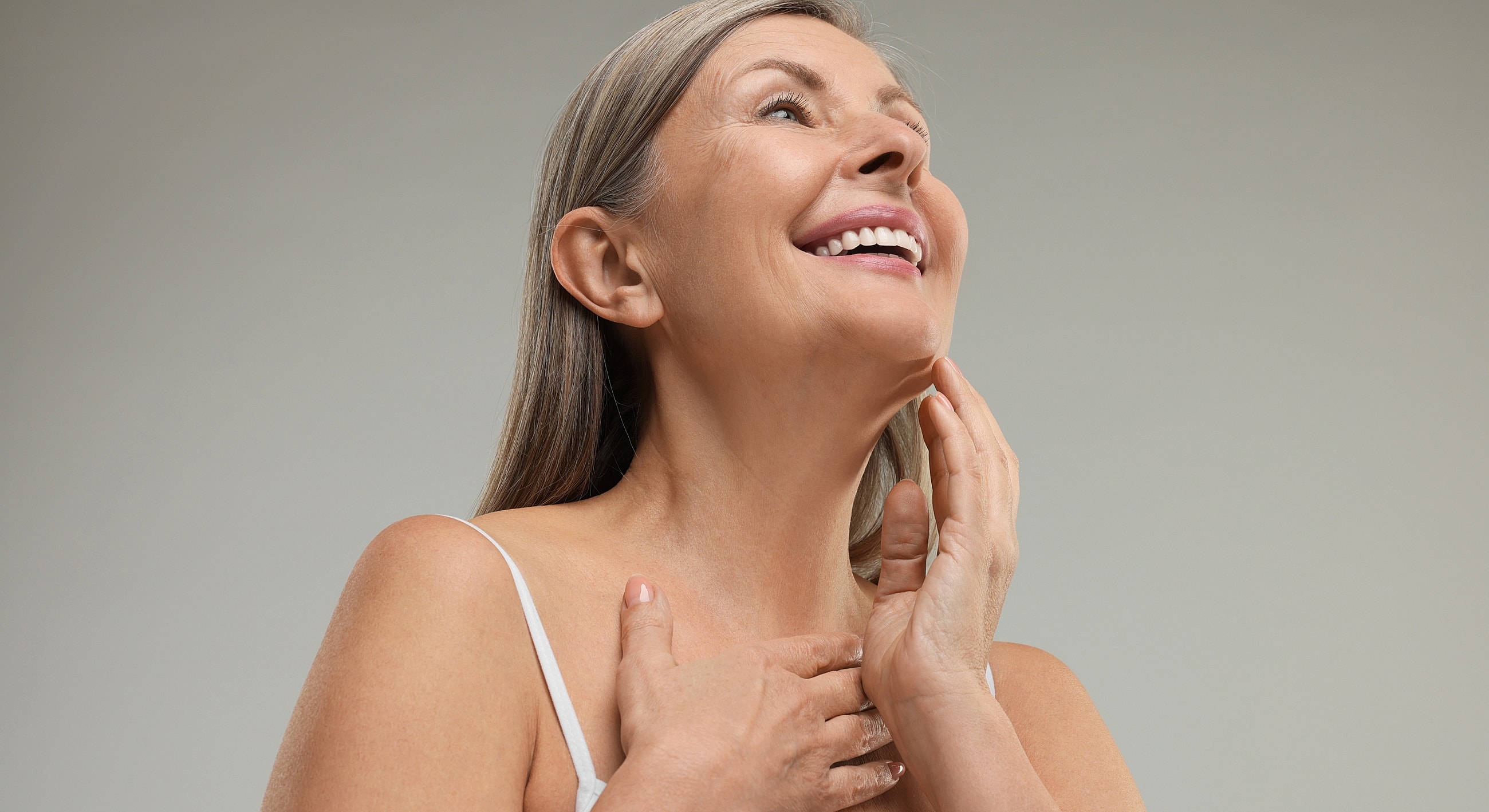 Smiling woman touching her face gently.