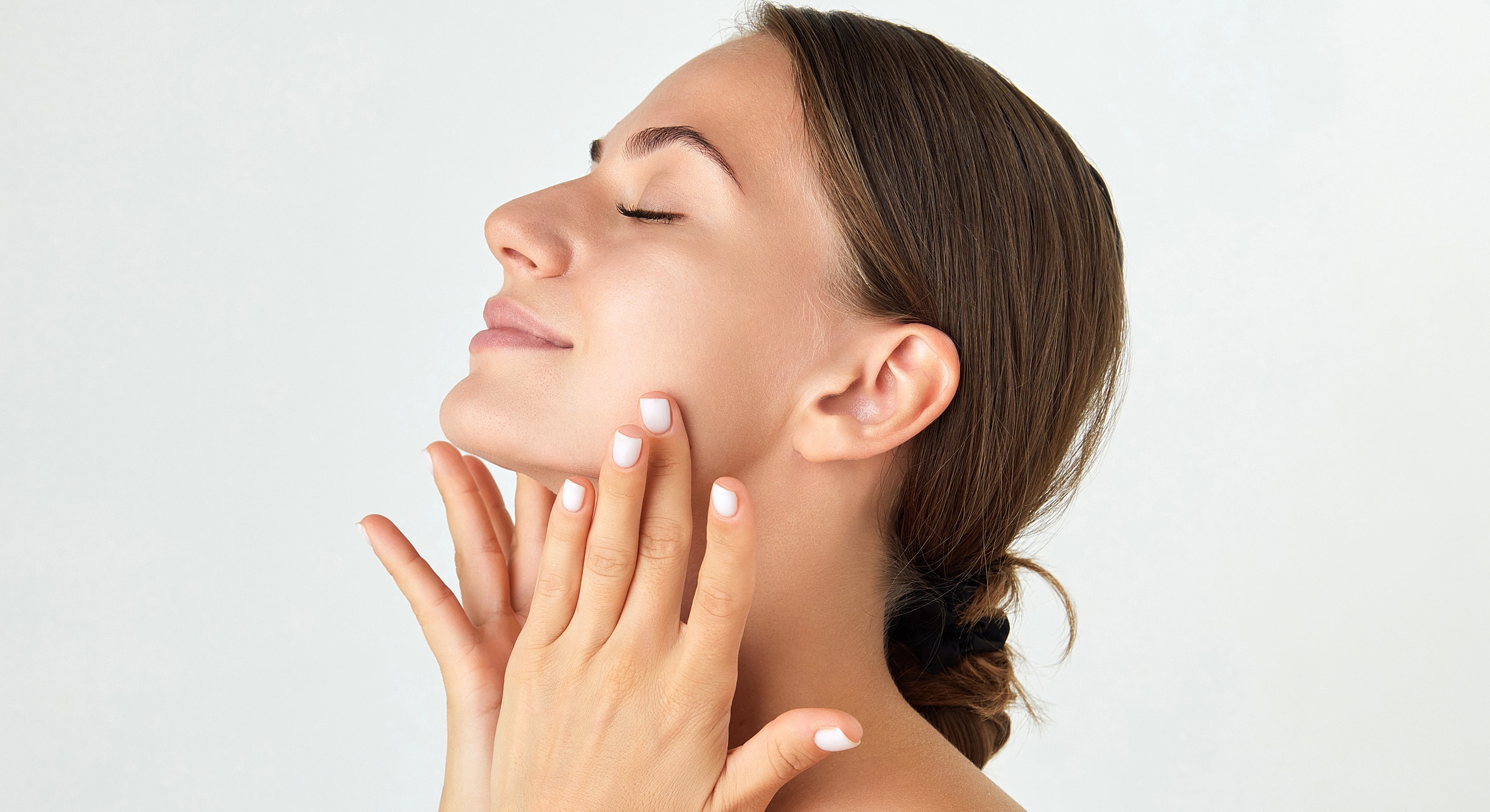 Woman applying skincare with serene expression.