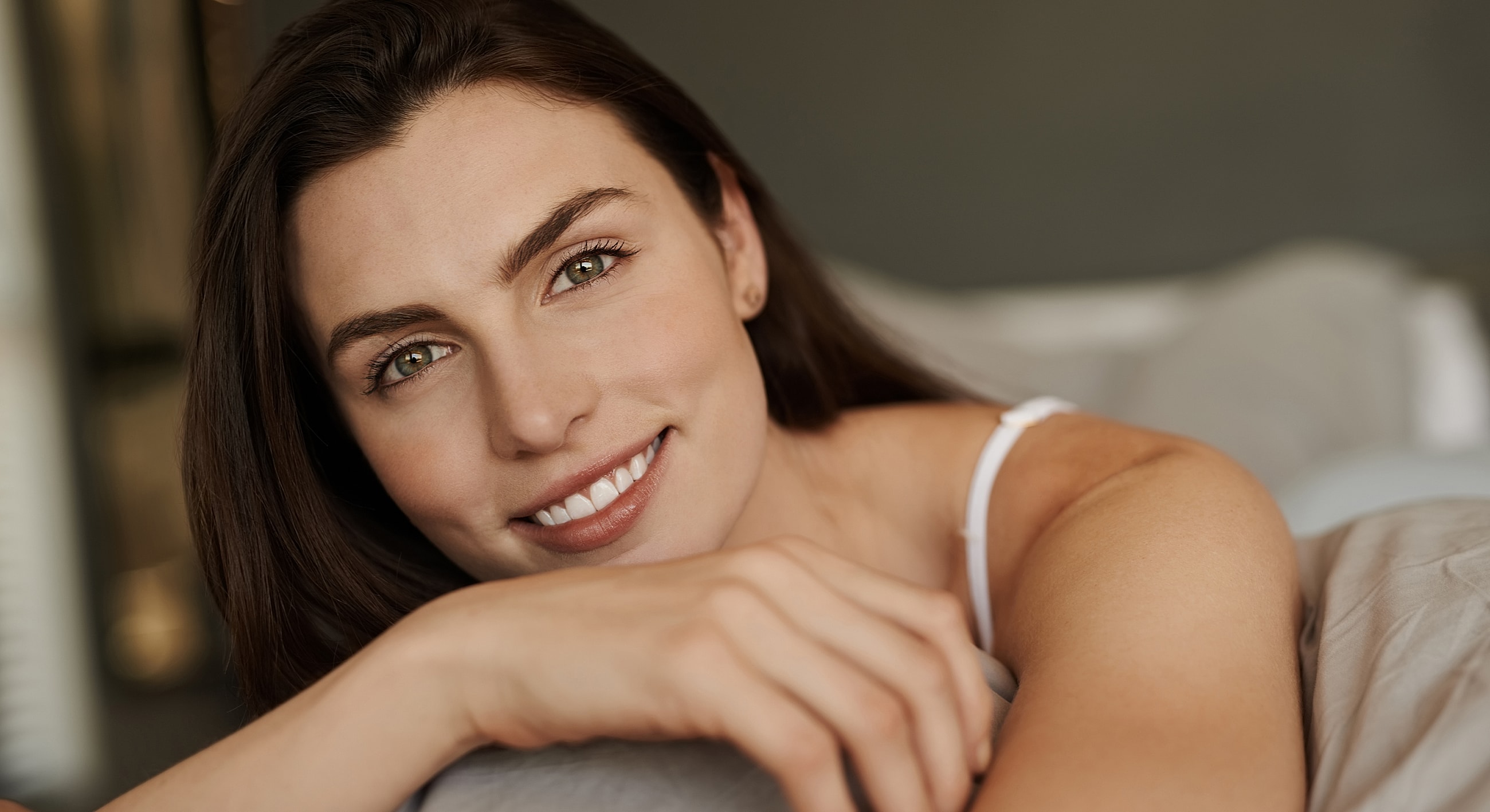 Smiling woman resting on a bed.