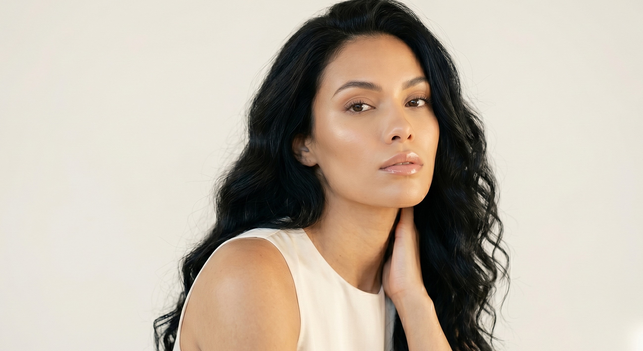 Woman with long, wavy black hair posing elegantly.